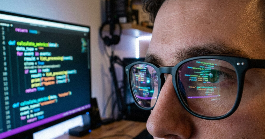 A close up of computer code on a monitor reflecting in a person's glasses. [Anthropic Mythos 5]