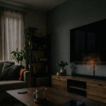 OLED television appearing to be off in a dark living room while its built-in microphone remains active.