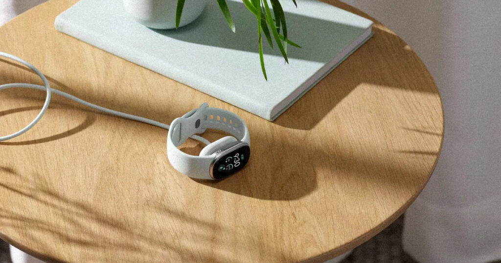 Fitbit Edge on a fast magnetic charger beside a cup of tea