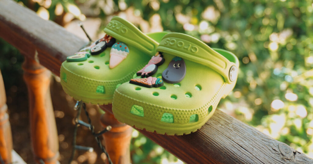 Child pressing a Jibbitz charm into a blue Crocs clog